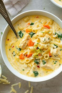 two bowls filled with chicken noodle soup on top of a table