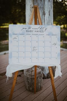 an easel with a calendar on it sitting in front of a tree