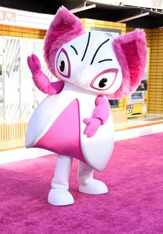 the pink and white character is standing on a purple carpet in front of a building