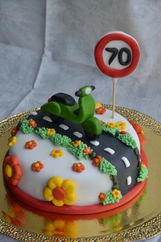 a birthday cake decorated with flowers and a motorcycle on the road is for 70th birthday