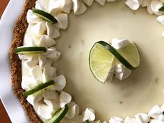 a white plate topped with a pie covered in whipped cream and lime slices