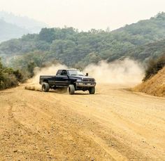 a black truck driving down a dirt road