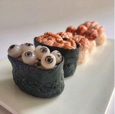 three sushi rolls decorated with googly eyes