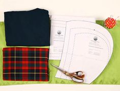 sewing supplies laid out on top of a green table cloth with scissors and fabric next to it