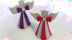 two christmas angel figurines made out of glittery paper with bows on them