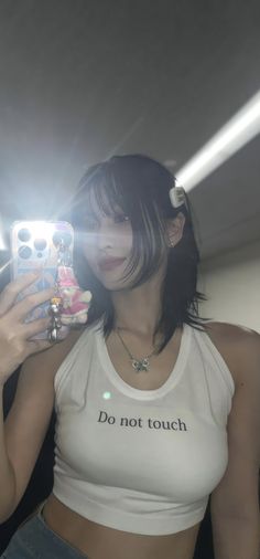 a woman taking a selfie in the mirror with her cell phone while wearing a white tank top