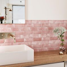 a bathroom with pink tiles on the wall and a white sink in front of it