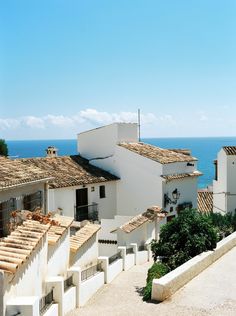 an aerial view of some white buildings and the ocean in the backgrouds