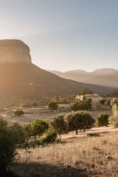 the sun shines brightly on an arid landscape with trees and mountains in the background