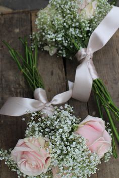 two bouquets of flowers sitting on top of a wooden table next to each other