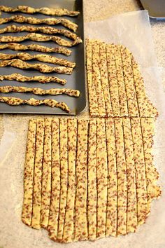 crackers are lined up on a baking sheet next to a pan with one cut in half