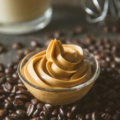 a glass bowl filled with peanut butter on top of coffee beans