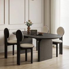 a dining table with four chairs around it and a vase on the table next to it