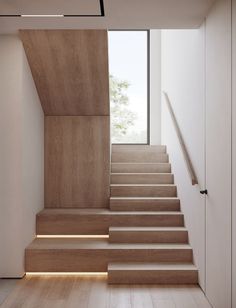 the stairs are made of wood and have light coming from them on each side, along with white walls