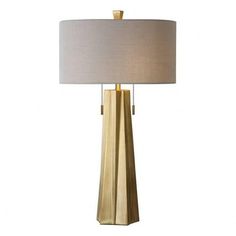 a table lamp with a white shade on it and a gold finish metal frame base