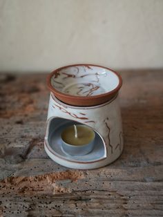 a white and brown candle holder sitting on top of a wooden table