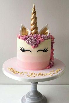 a birthday cake decorated with an unicorn's face and pink frosting, topped with flowers