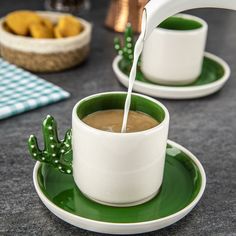 a person pouring milk into a cup on a green saucer with cactus decorations around it