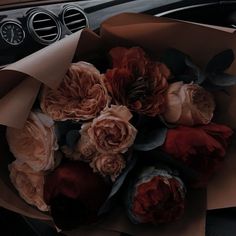 a bunch of flowers sitting inside of a brown paper bag on top of a car dashboard