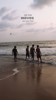 four people walking on the beach with their feet in the water and one person holding his hand out