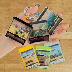 a person holding four small cards in their hand, one with a keychain on it