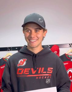 a young man in a devils hoodie holding a sign