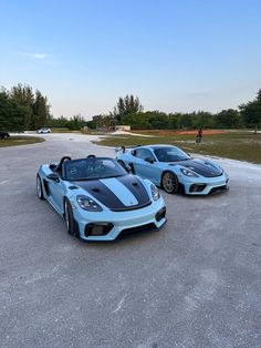 two blue sports cars parked in a parking lot