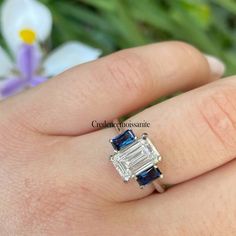 a woman's hand holding a ring with two blue and white stones on it