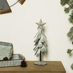 a wooden christmas tree sitting on top of a table next to a mirror and pine cones