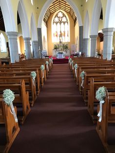 rows of pews in a church decorated with flowers and ribbons for the bride's bouquet