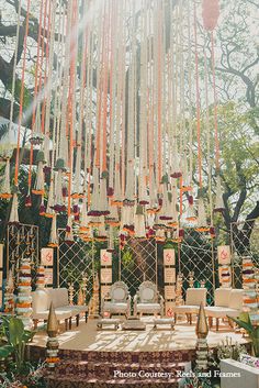 an outdoor ceremony set up with chairs and flowers on the stage, surrounded by greenery