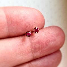 **Please note: My current production time is 5-10 business days.** Tiny Ruby Studs Wow! These are truly stunning! Gorgeous 3mm red ruby gemstones are prong set in lovely solid 14k gold settings. Simple and classic, these stud earrings are perfect for everyday. Each sparkly gemstone is handset and includes 14k solid gold backs. Every Marigold Mary purchase will arrive beautifully packaged in a small gift box. View my other earrings here: https://www.etsy.com/your/shops/marigoldmary/sections/14493 Red Dainty Earrings For Anniversary, Dainty Red 14k Gold Earrings, Classic Ruby Red Earrings, Gold Ruby Round Earrings, Gold Marquise-cut Ruby Jewelry, Single Ruby Earring In Red, Red Round Cut Birthstone Earrings, Red Ruby Birthstone Earrings, Red Ruby Earrings Studs