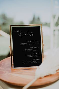 a table with a sign that says the drinks on it and some feathers sitting next to it