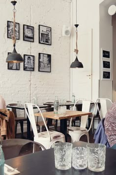 a woman sitting at a table in a room with chairs and pictures on the wall