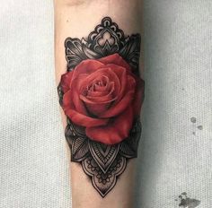 a red rose tattoo on the left forearm and arm with an ornate border around it