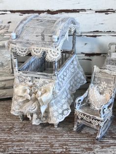 two miniature chairs are sitting next to each other on a wooden table with white lace