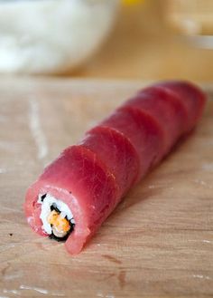 a piece of sushi sitting on top of a wooden cutting board