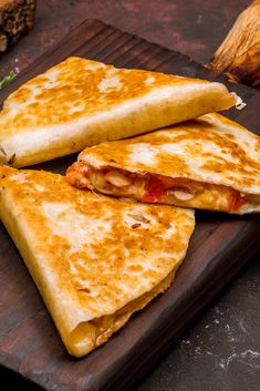 two quesadillas cut in half sitting on a cutting board next to other food items