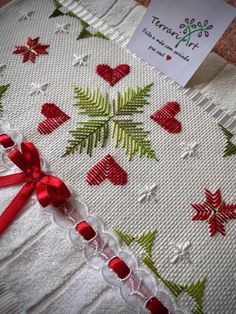 a white blanket with red and green designs on it, next to a tag that says tamper tree