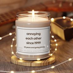 a candle that is sitting on top of a table with string lights around it and the words, annoying each other since 1999