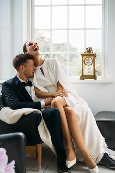 a man and woman sitting next to each other on a couch in front of a window