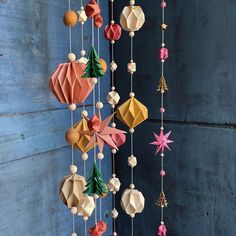 an origami mobile hanging on a blue wall with stars and christmas decorations attached to it