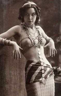 an old fashion photo of a woman in a belly ring and skirt with pearls on her head