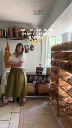 a woman standing in front of a counter filled with baked goods next to shelves full of bread