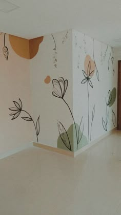 an empty room with flowers painted on the wall and flooring in front of it