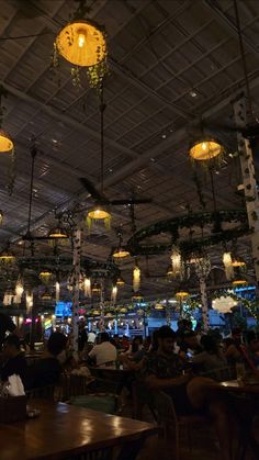 a restaurant filled with lots of people sitting at tables and hanging from the ceiling above them