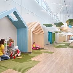 two children are playing with toys in a playroom that has green carpet and white walls