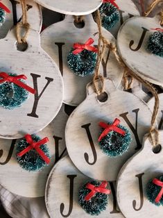 christmas ornaments are hanging from twine and decorated with red ribbon, bows, and letters