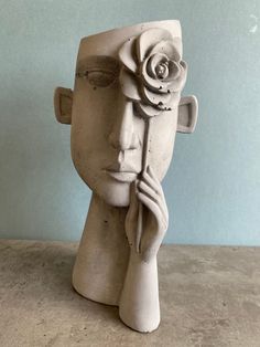 a sculpture of a woman's head with a rose in her hair on top of it