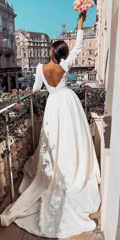 a woman in a white wedding dress standing on a balcony with her back to the camera